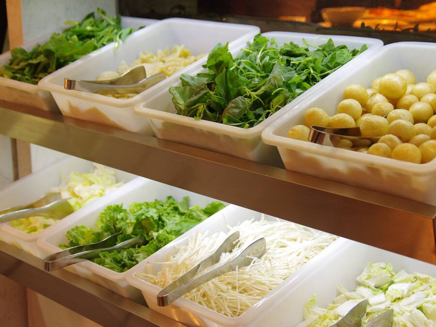 A buffet with various food items including greens, cheese, and other prepared dishes.