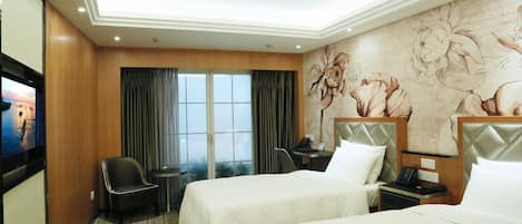 Une chambre d’hôtel avec deux lits, un bureau, une chaise, une télévision et une grande fenêtre avec des rideaux.