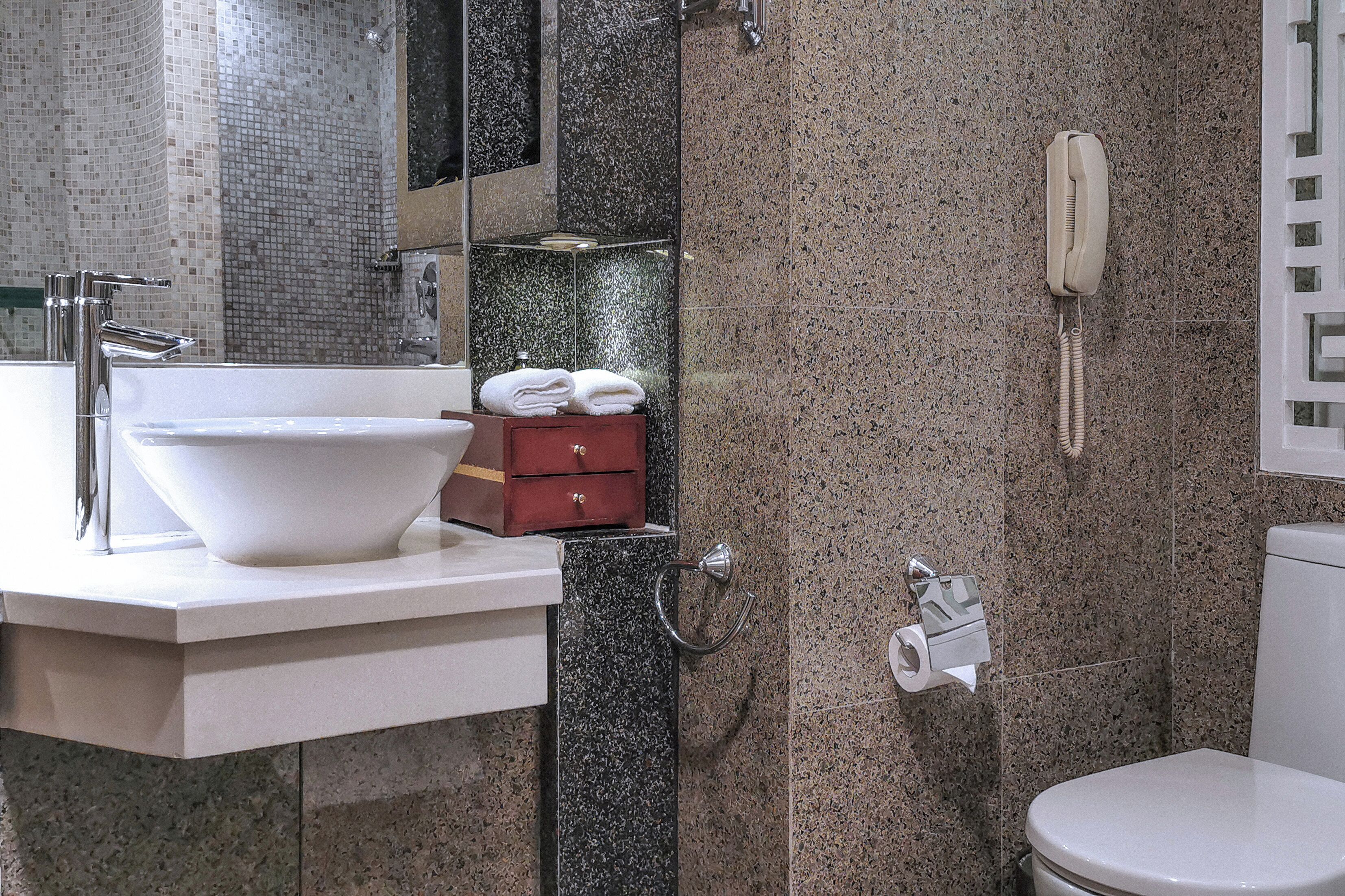 A modern bathroom with a white sink, a mirror, a toilet, and a shower area.