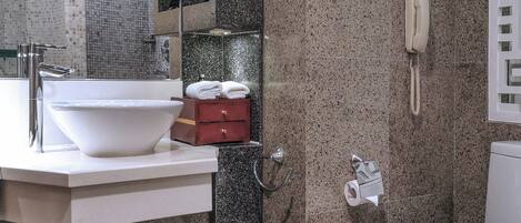 A modern bathroom with a white sink, a mirror, a toilet, and a shower area.