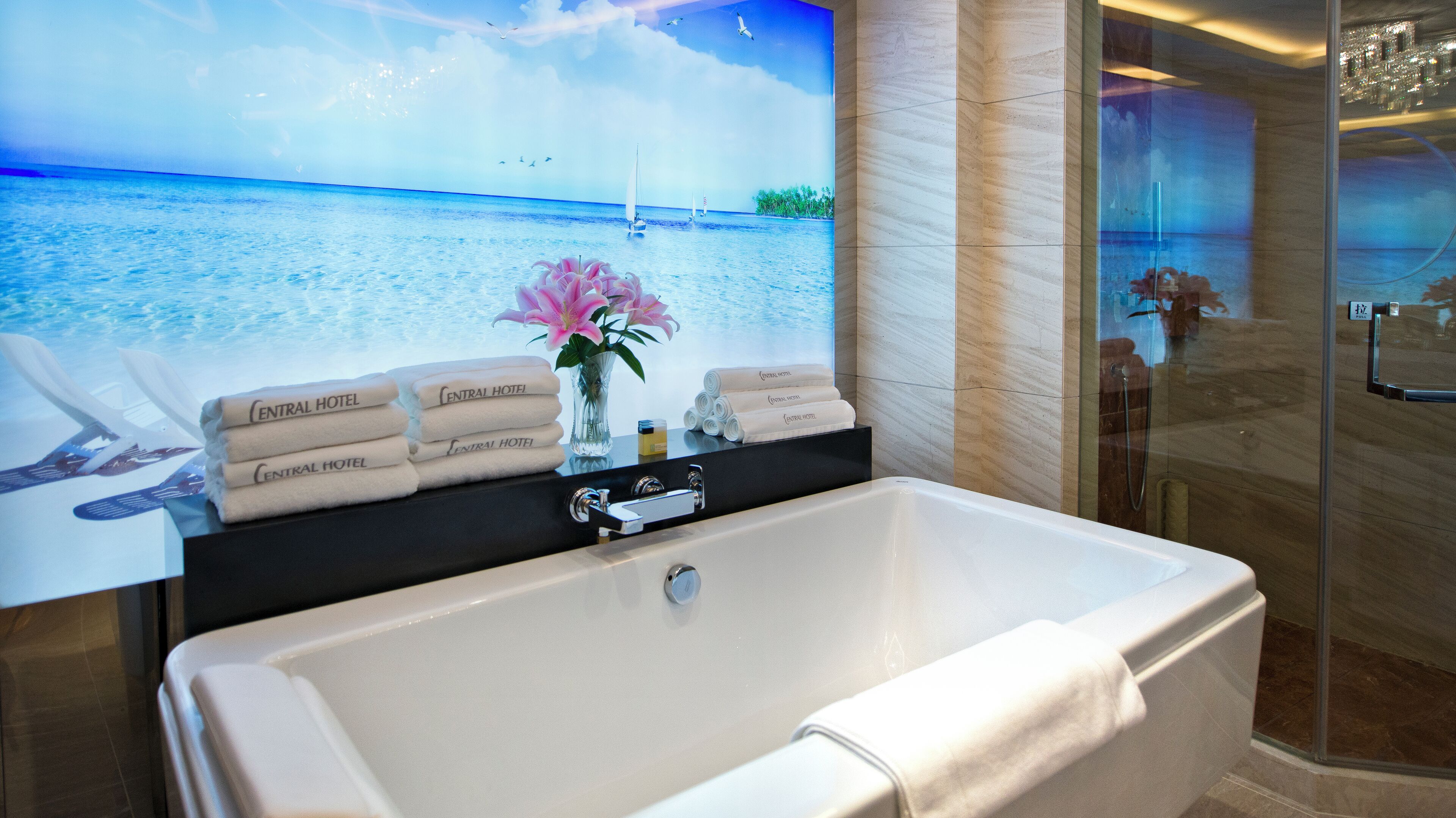 A bathroom with a large bathtub, a glass shower enclosure, and a wall-mounted towel rack with towels.