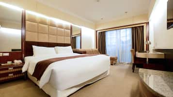 A hotel room with a large bed, a bedside table with a lamp, a chair, and a bathroom with a sink and mirror.