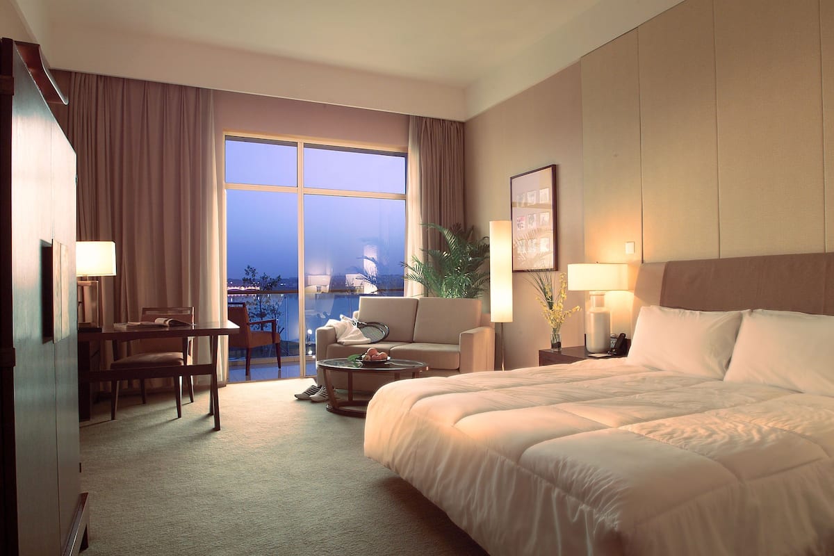 Hotelkamer met een groot bed, een bureau, een stoel, een bijzettafeltje en uitzicht op de stad.