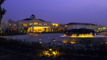 A modern hotel with a large fountain in the courtyard, surrounded by well-maintained landscaping.