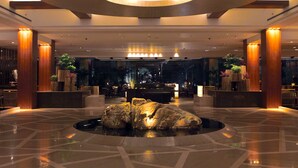 A spacious lobby with a central rock feature, a reception desk, and a modern chandelier. - Jinling Resort Nanjing (Nanjing)