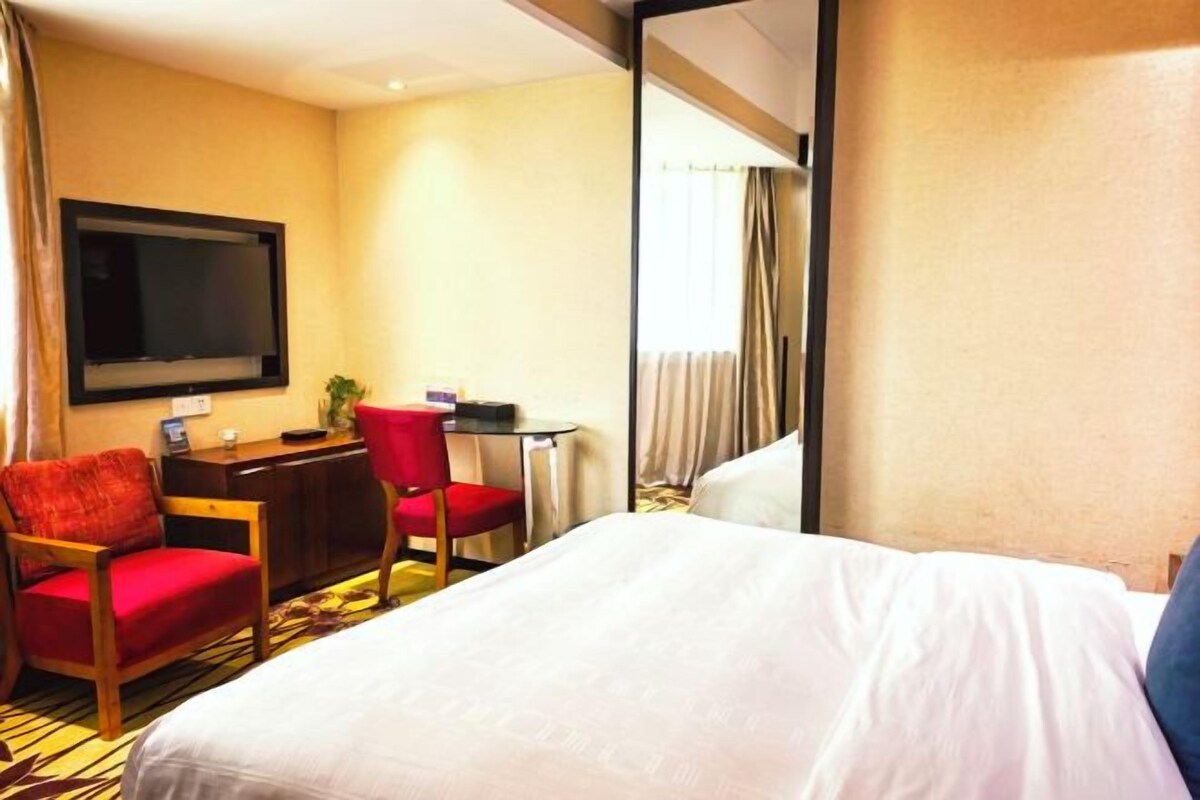 Ein Hotelzimmer mit Bett, Schreibtisch, Stuhl und Fernseher.
