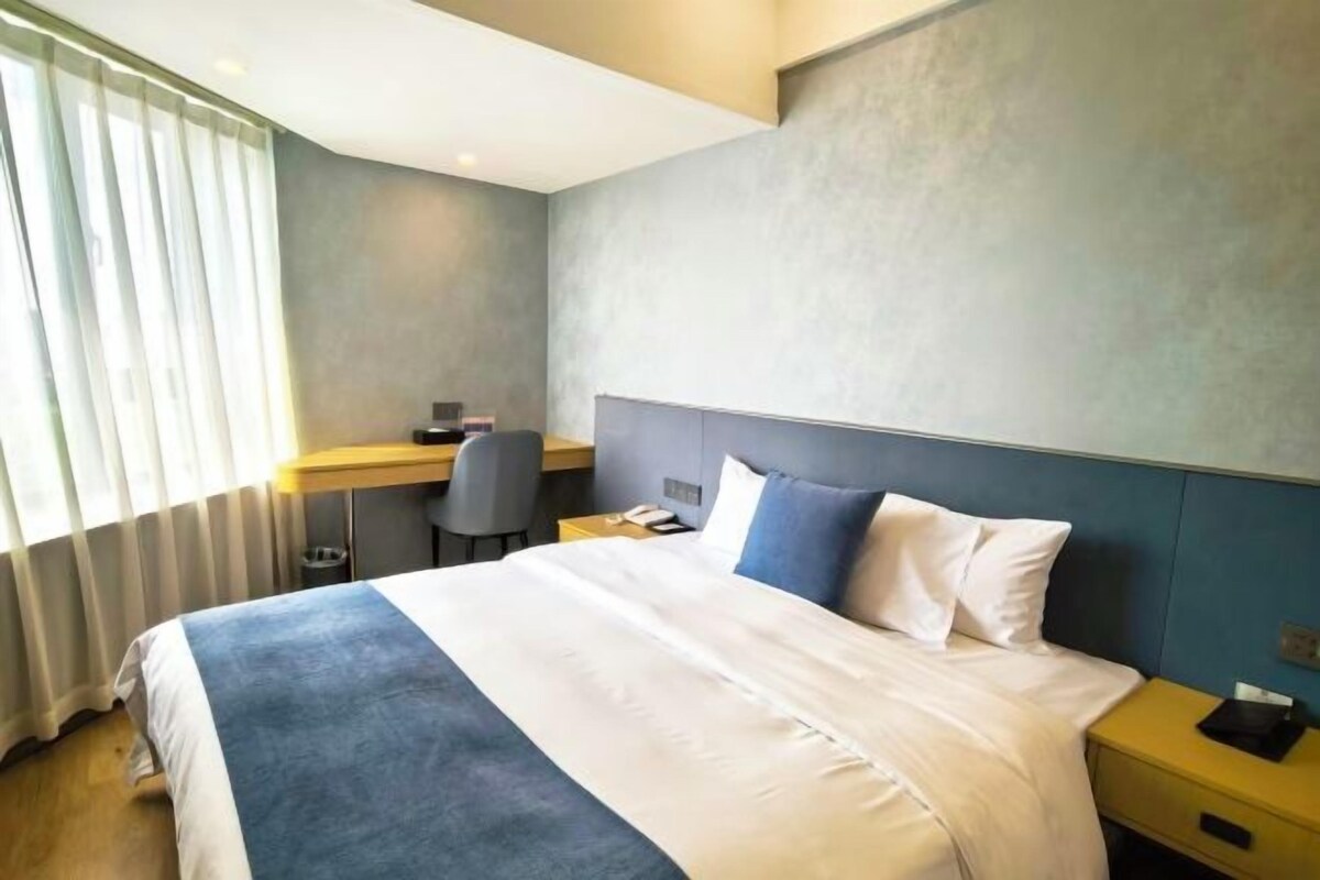 Ett hotellrum med en säng, ett skrivbord och en stol.