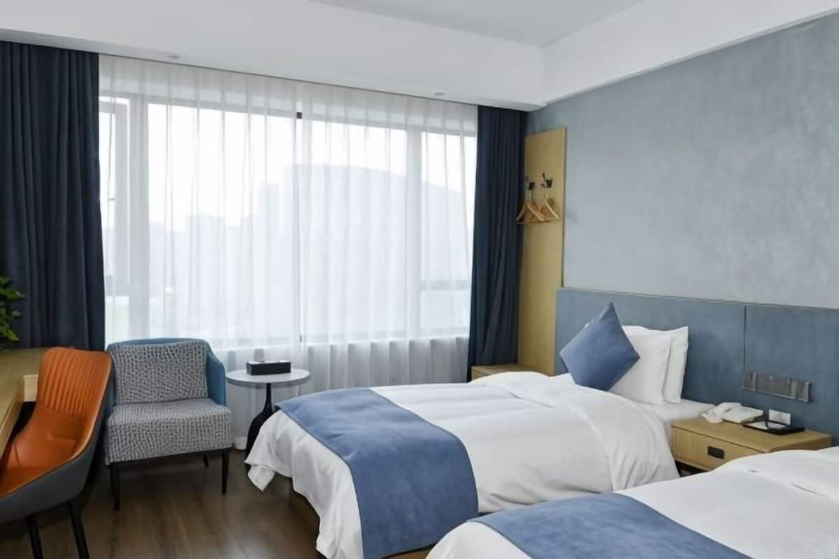 A hotel room with two beds, a small table, a chair, and a desk.