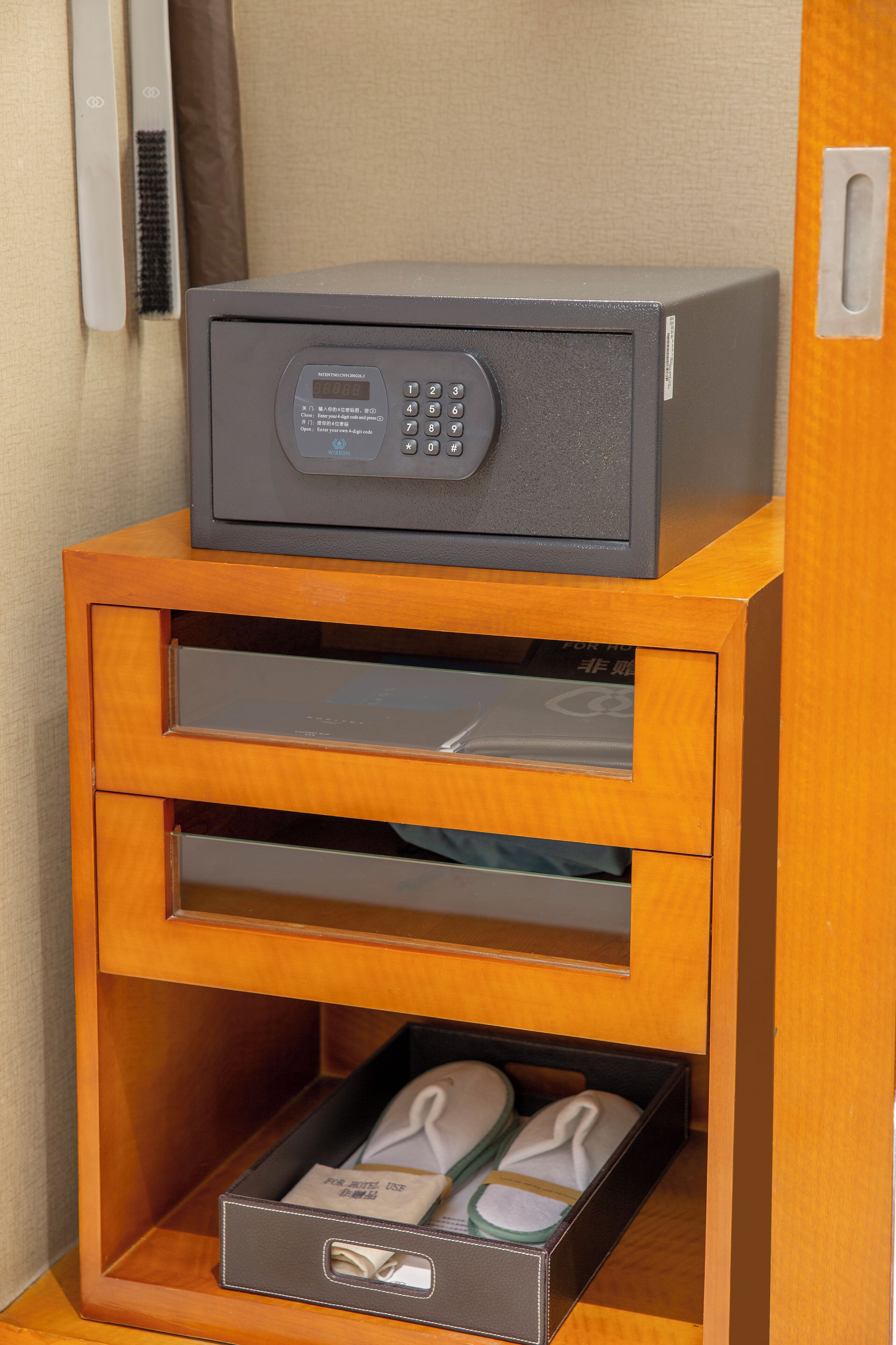 A wooden cabinet with a microwave on top, a drawer with a box of slippers, and a shelf with a pair of shoes.