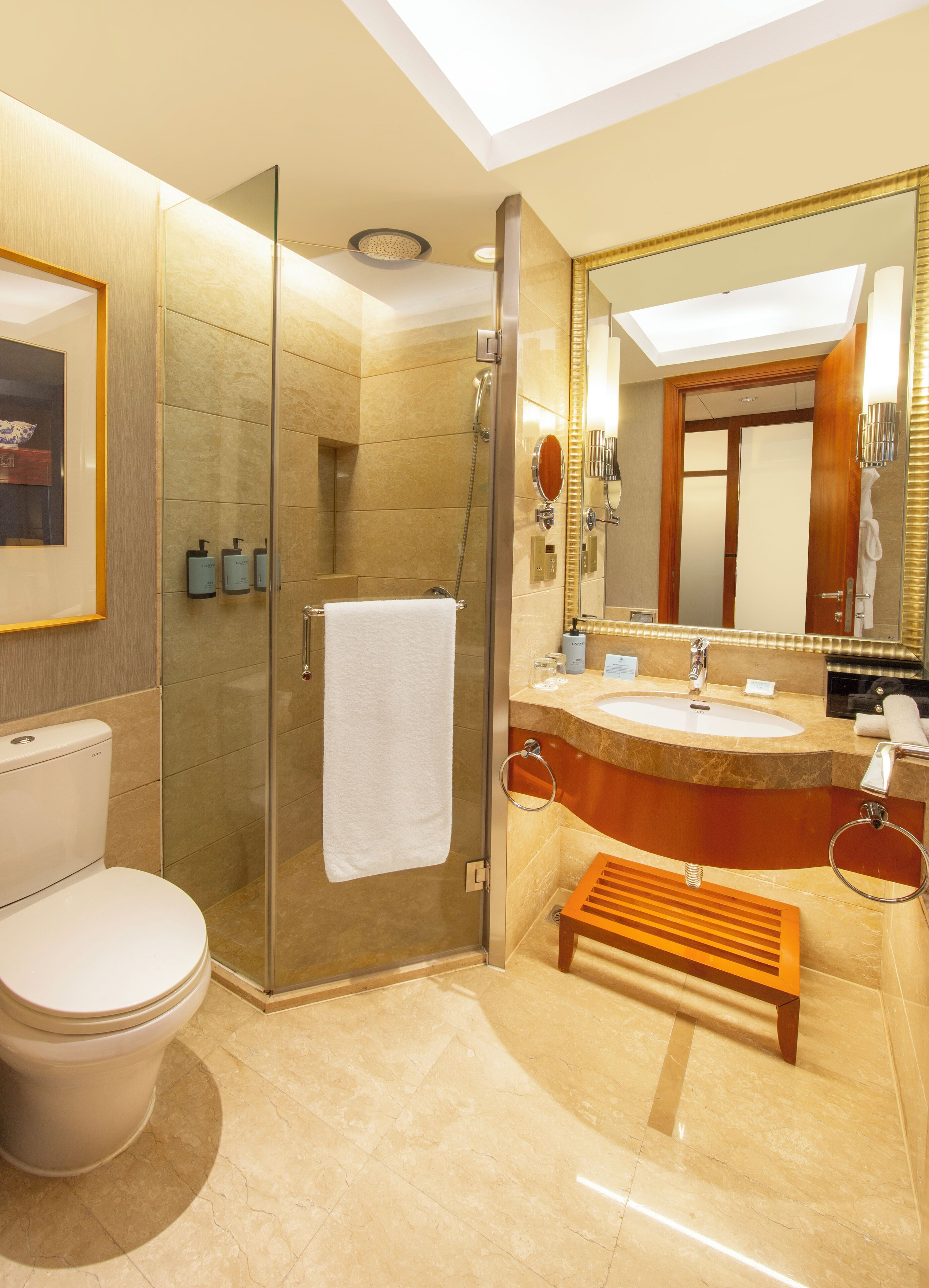 A modern bathroom with a glass-enclosed shower, a toilet, a sink with a vanity, and a large mirror.