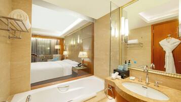 A modern hotel bathroom with a large bathtub, a sink, and a mirror.