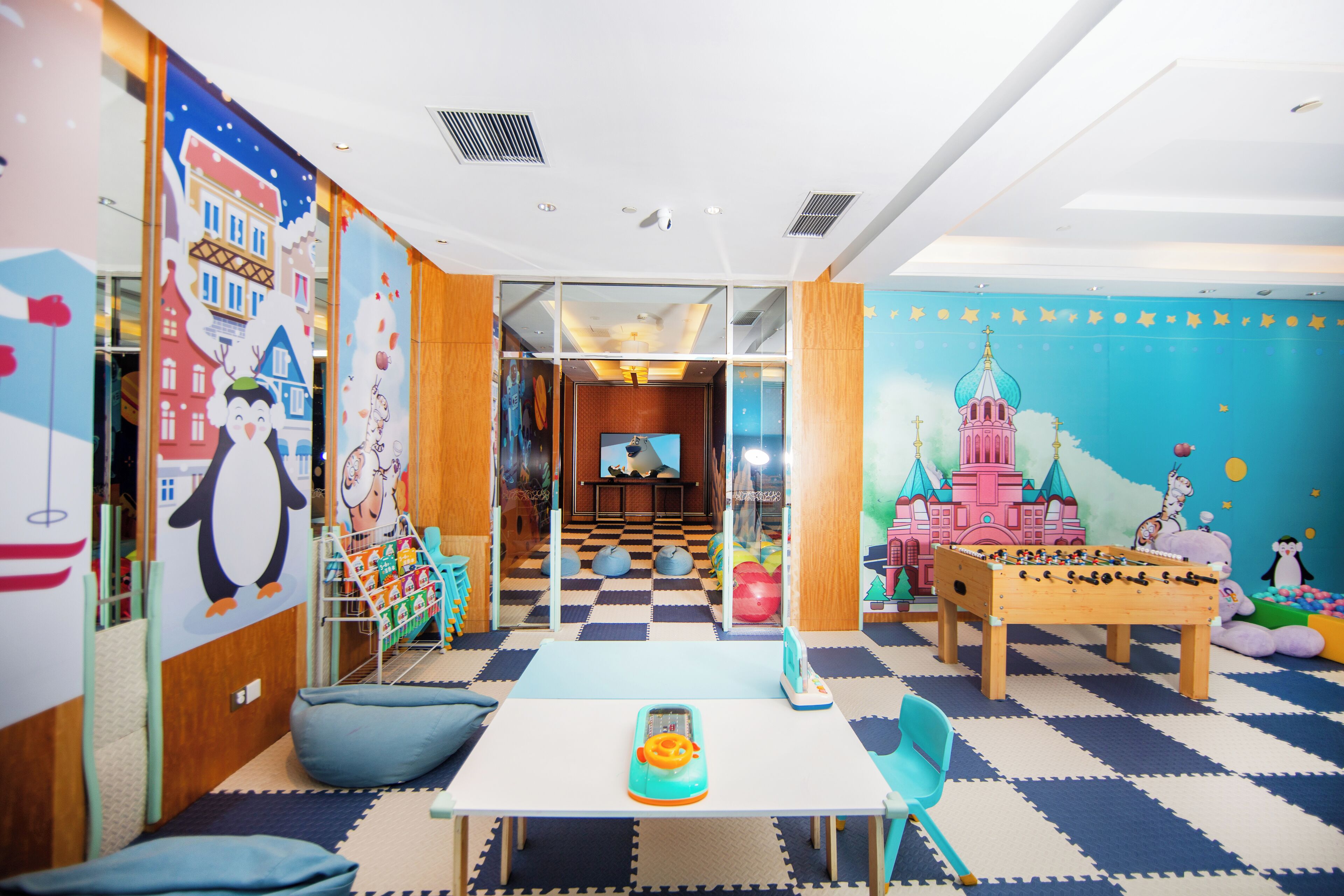 Un cuarto de juegos infantil con mesa de futbolín, una mesa con juguete y decoraciones de pared coloridas.