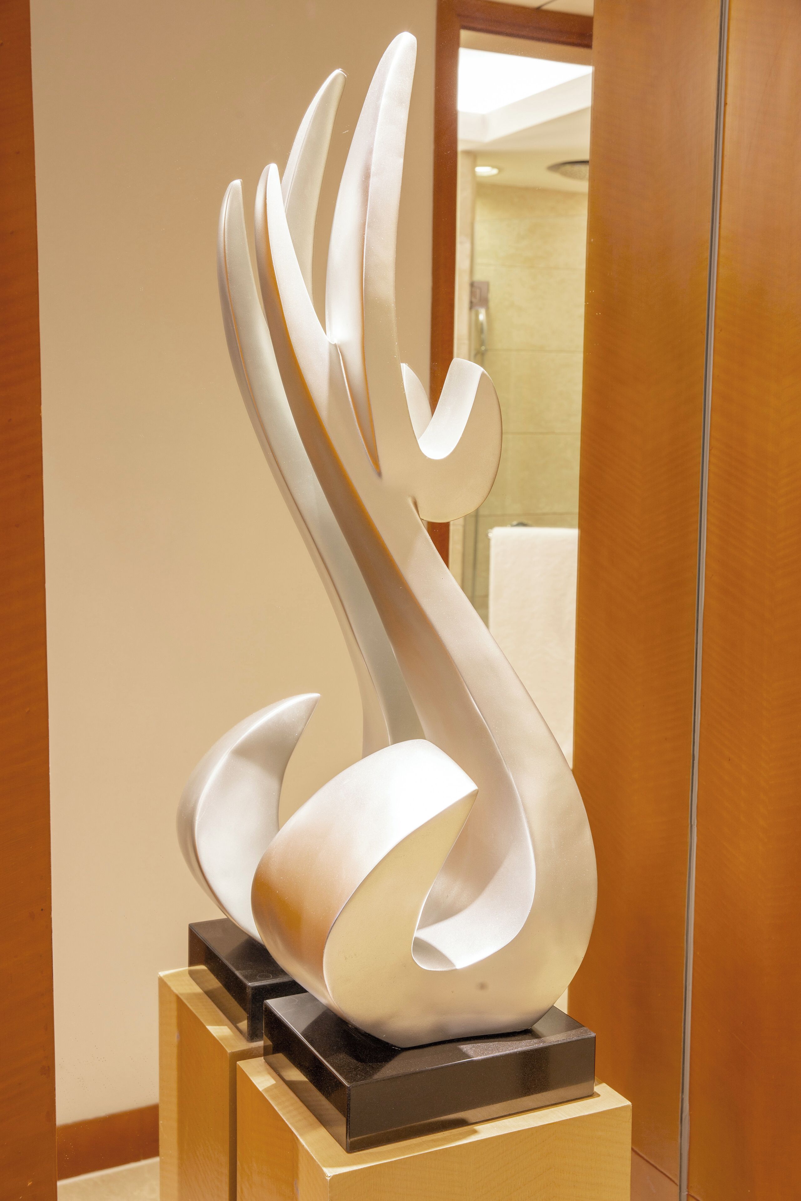 A modern sculpture on a pedestal in a lobby area.
