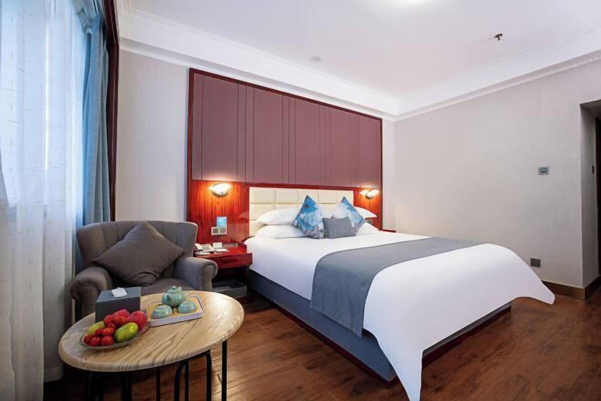 Una habitación de hotel con una cama, una zona de estar con mesa y una mesita de noche.