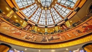 A grand atrium with a high ceiling and a glass dome, featuring a central chandelier and a mural depicting historical scenes. - Zhongdu Hotel (Zhengzhou)