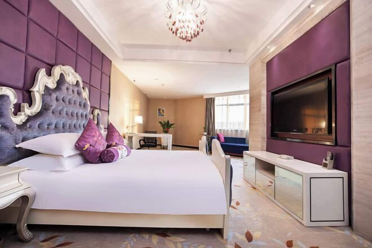Una habitación de hotel con una cama grande, un televisor, un escritorio y una zona de estar.