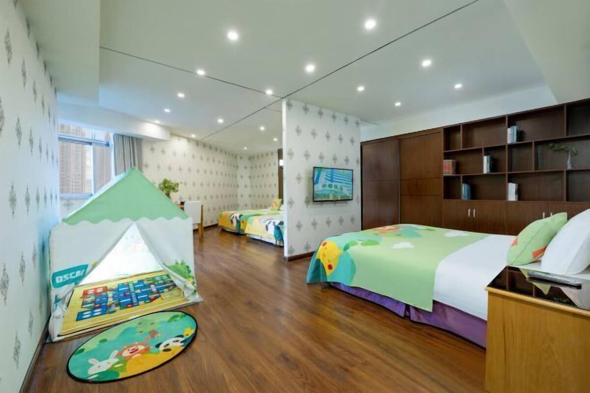 Una habitación infantil con una tienda de juegos, literas, un televisor y una estantería.