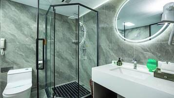 Un baño moderno con ducha envuelta en vidrio, un lavabo blanco y un espejo redondo.