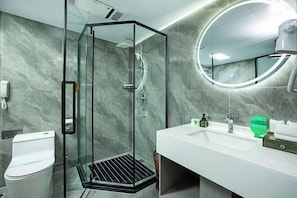 A modern bathroom with a glass-enclosed shower, a white sink, and a round mirror. - Zhongdu Hotel (Zhengzhou)