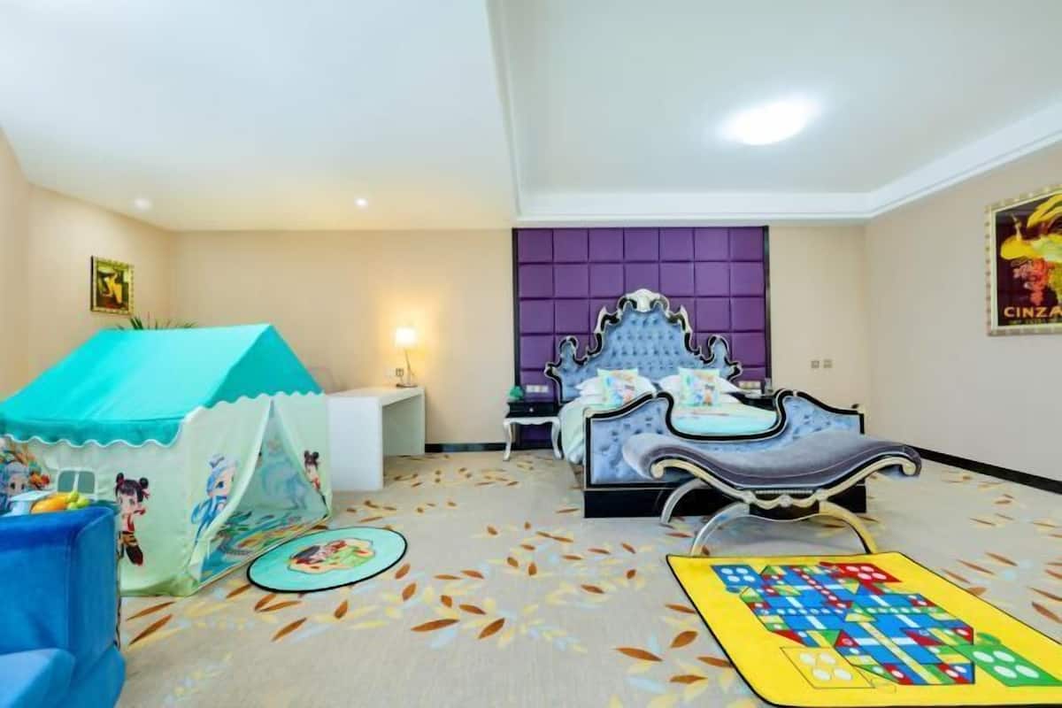 Un dormitorio con una cama, una tienda de juegos, un tapete y un cartel en la pared.