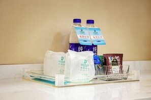 A tray with bottled water, tea bags, and a glass. - Zhongdu Hotel (Zhengzhou)