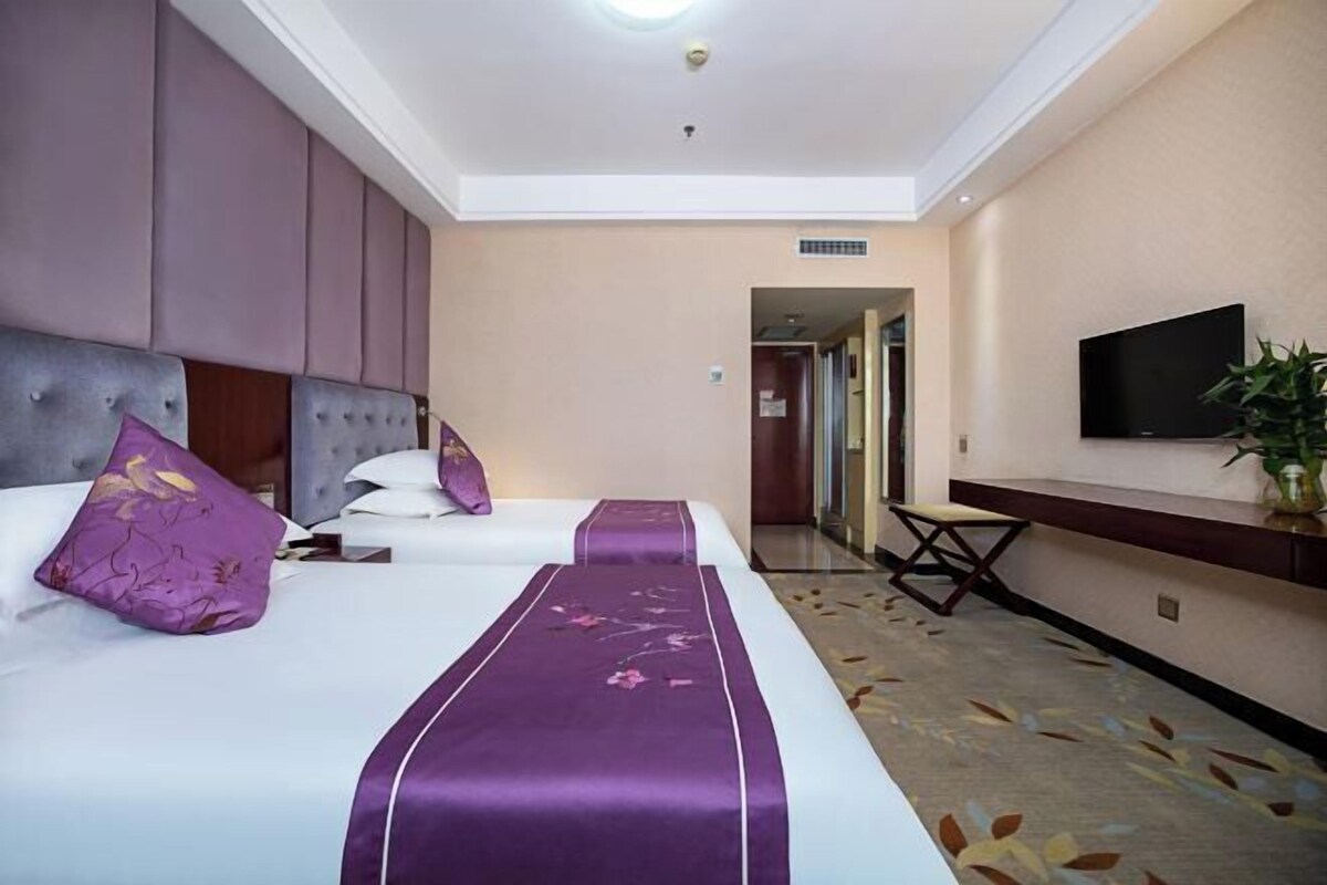 Ein Hotelzimmer mit zwei Betten, einem Fernseher und einem Schreibtisch.