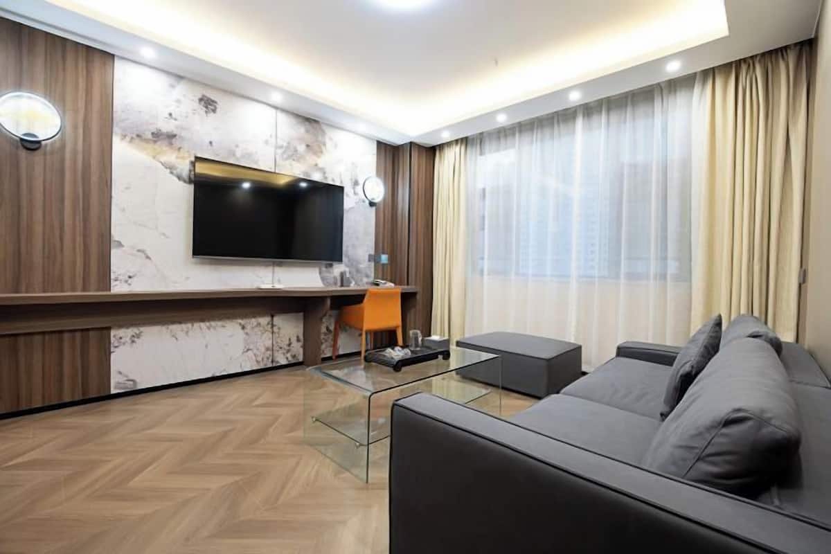 Una sala de estar moderna con un sofá, una mesa de centro, un televisor instalado en una pared de mármol y un escritorio con una silla.