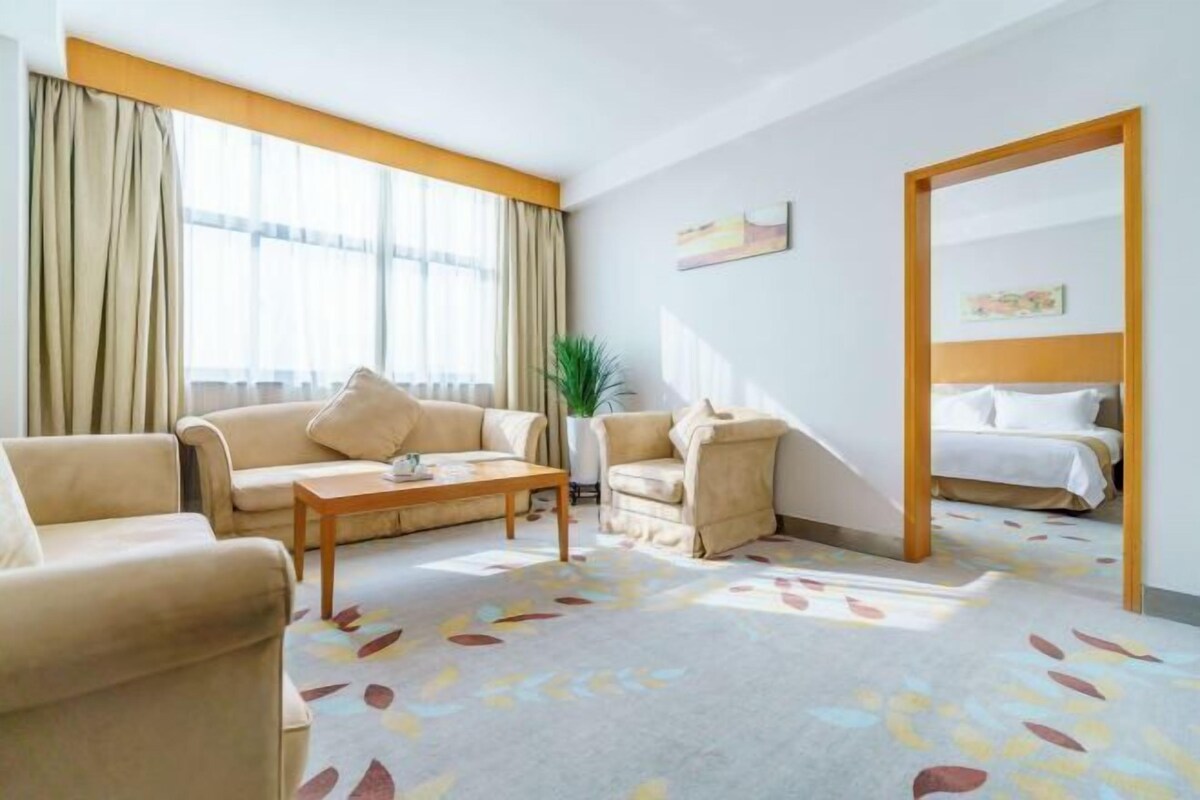 Ein Hotelzimmer mit Sofa, Sessel, kleinem Tisch und einem Bett.