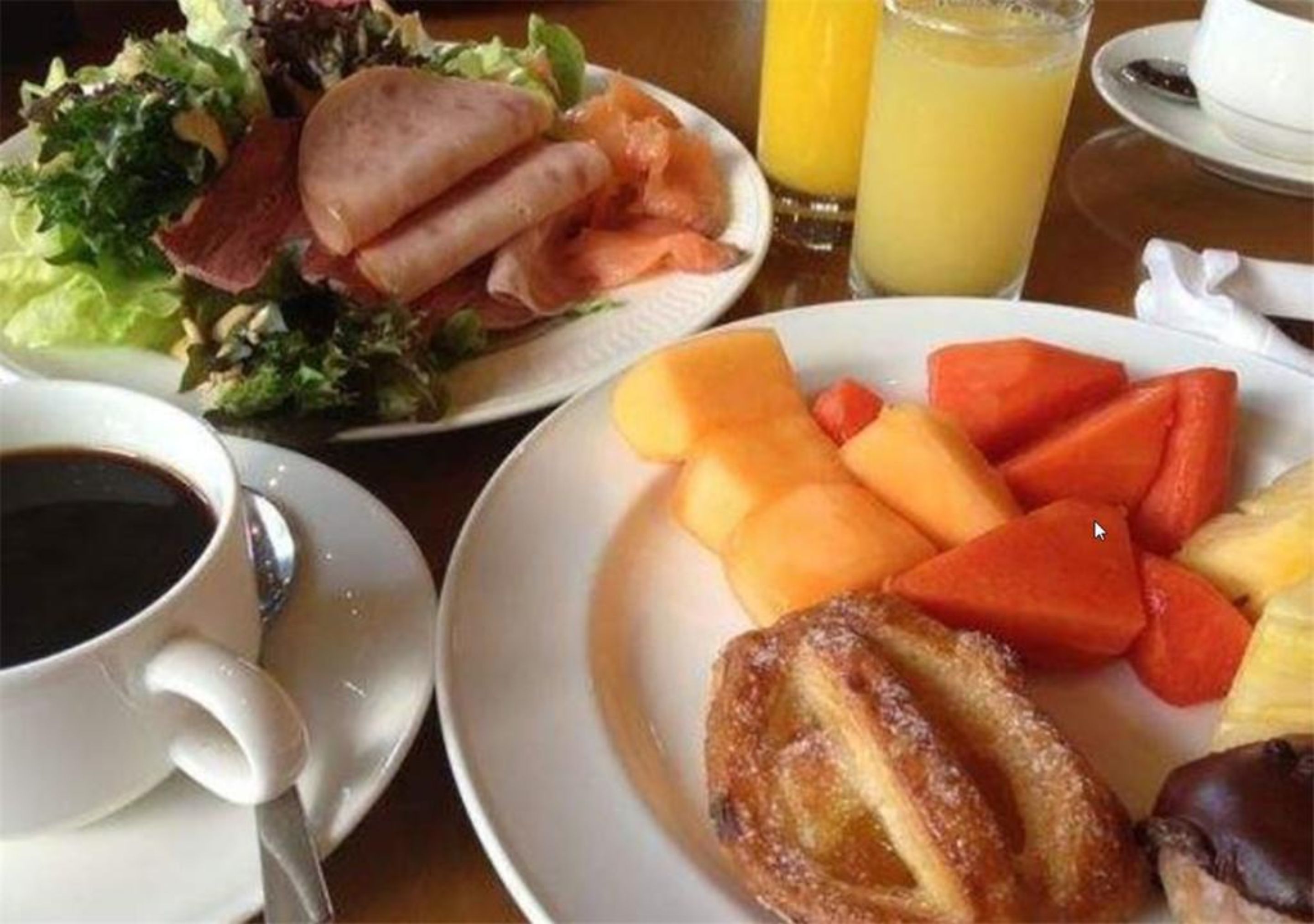 A breakfast setting with plates of food, a cup of coffee, and a glass of orange juice.