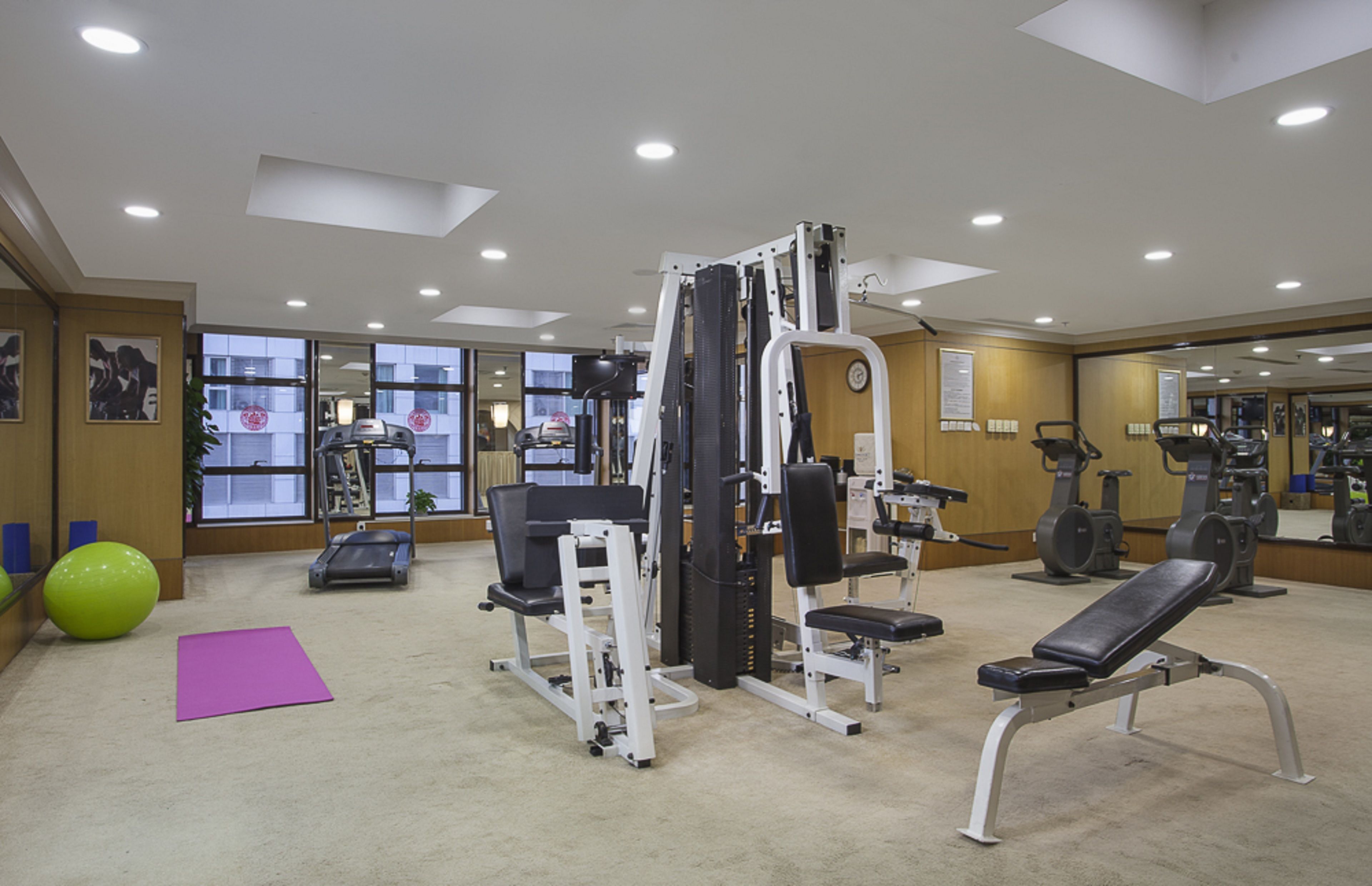 A gym with exercise equipment, a treadmill, and a large mirror.