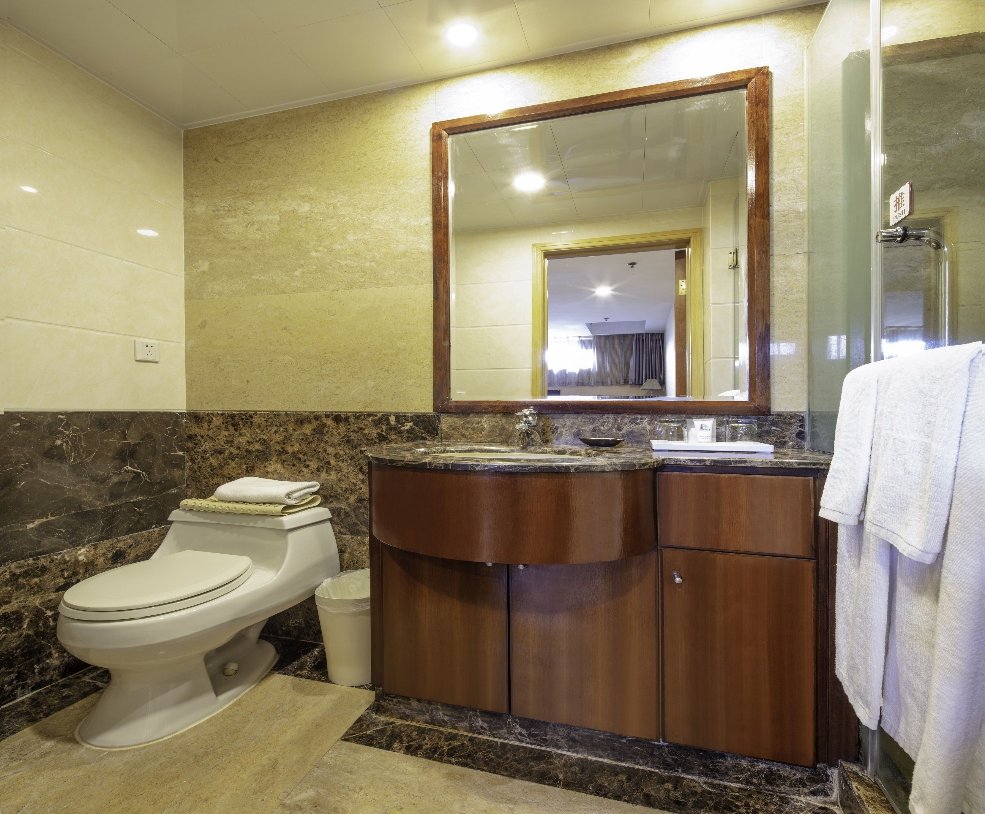 A bathroom with a toilet, sink, and mirror.