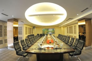A conference room with a long table, multiple chairs, and a large circular light fixture.