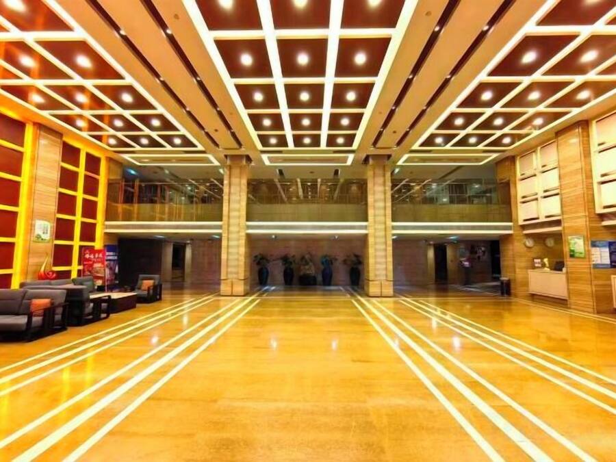 A spacious lobby with a polished floor, a reception desk, and a seating area with sofas.