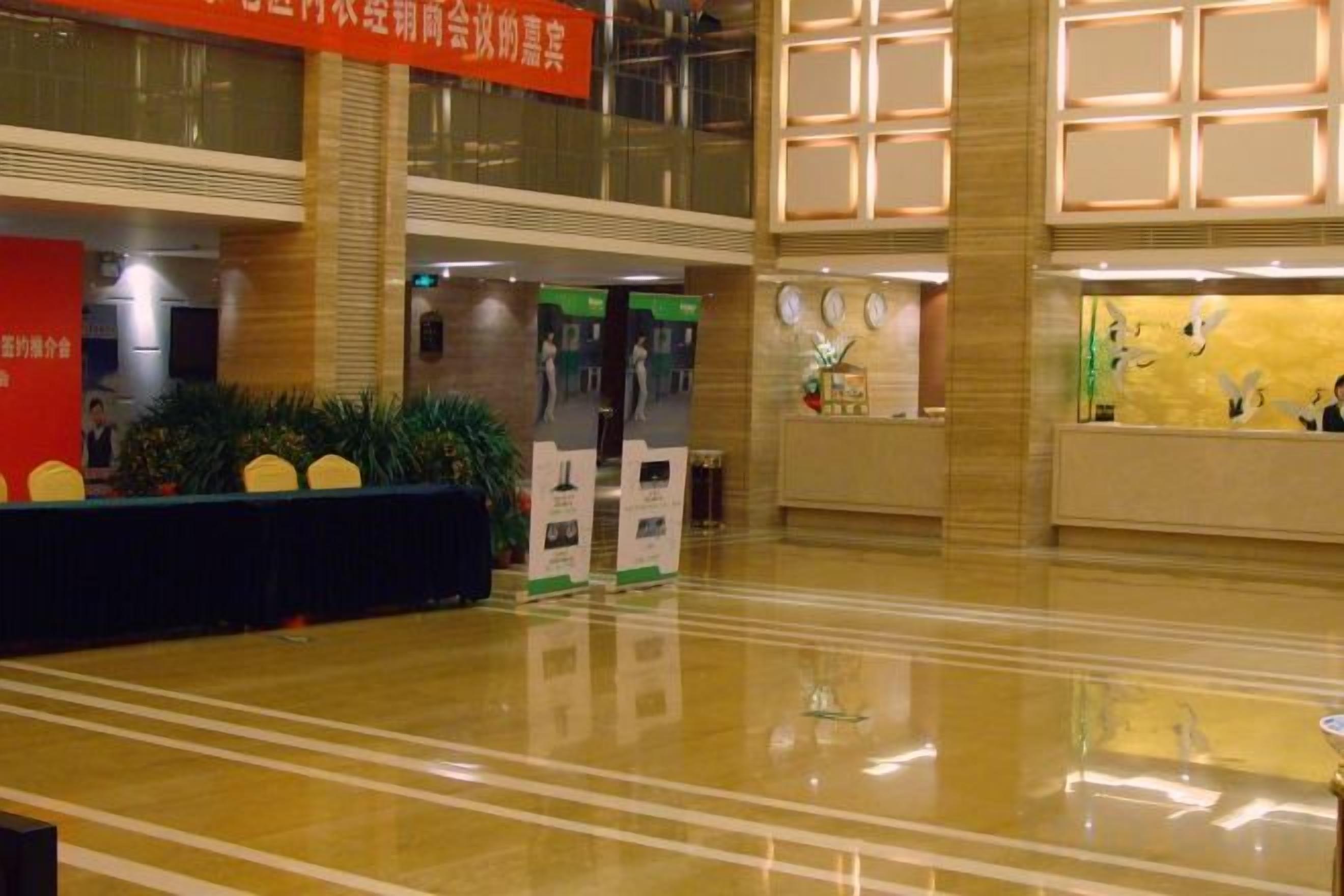 A hotel lobby with a reception desk, a seating area, and a large window.
