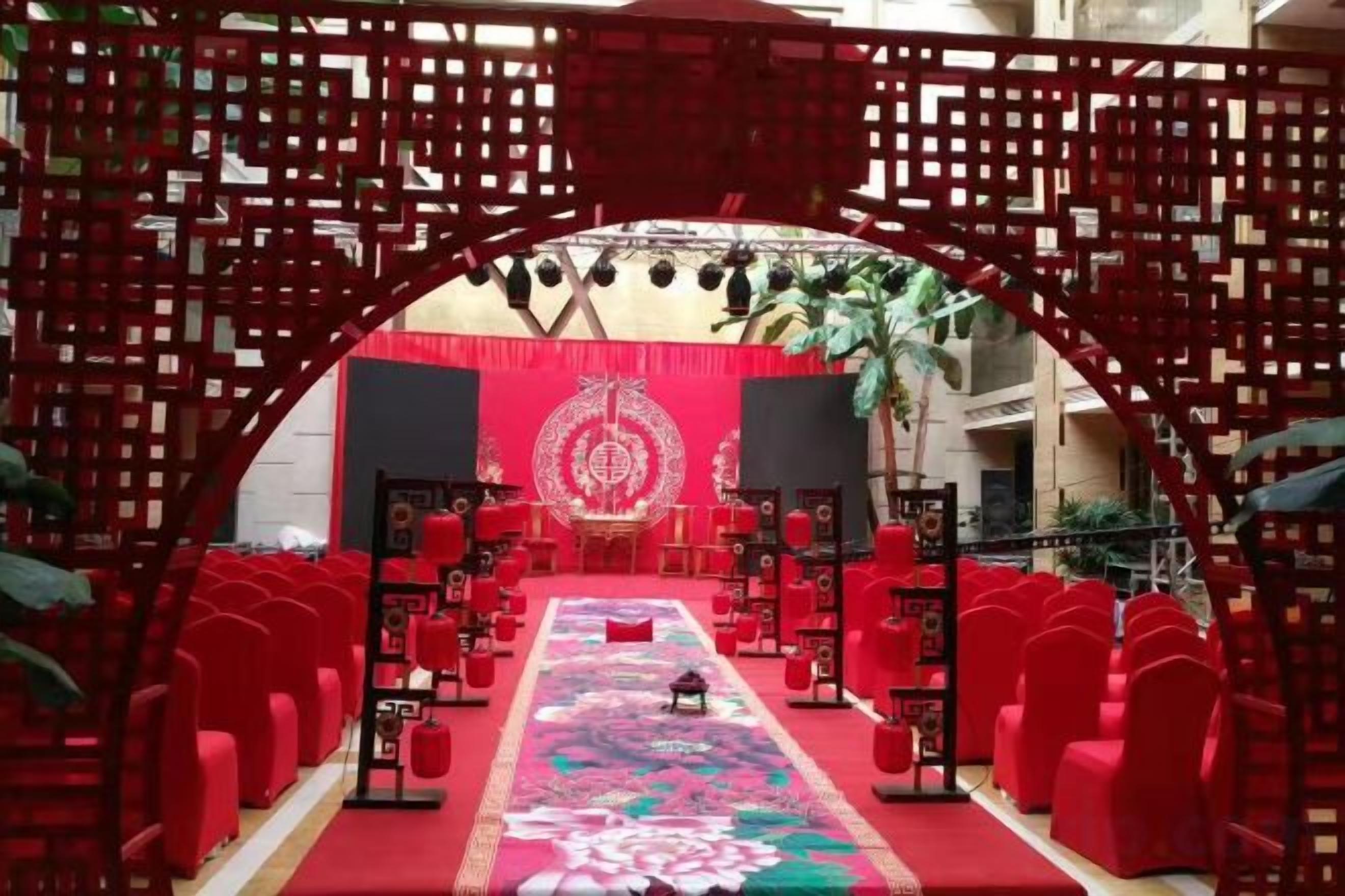 Une scène avec des chaises rouges et un tapis rouge, entourée d’une structure en treillis rouge.