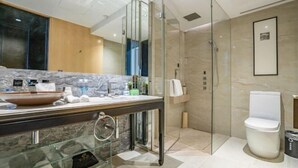 Un baño moderno con cabina de ducha de vidrio, encimera de mármol y váter blanco.