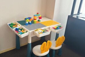 A children's play area with a table and chairs, featuring building blocks and a small toy structure. - Fortune Bond Hotel (Ningbo)