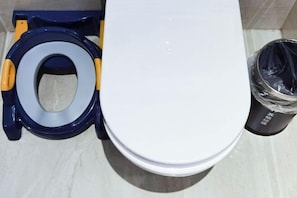 A white toilet with a blue and yellow seat, a white tank, and a black trash bin with a plastic bag. - Fortune Bond Hotel (Ningbo)