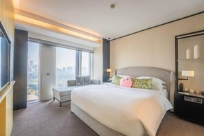 A hotel room with a large bed, a seating area, and a view of the city. - Fortune Bond Hotel (Ningbo)