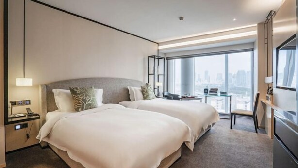 A modern hotel room with two beds, a desk, and a city view. - Fortune Bond Hotel (Ningbo)
