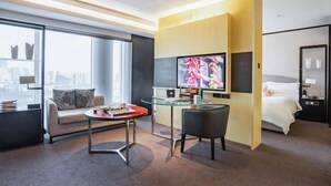 A modern hotel room with a large window, a sofa, a glass table, a TV, and a bed. - Fortune Bond Hotel (Ningbo)