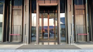 A modern building entrance with glass doors and a central elevator. - Fortune Bond Hotel (Ningbo)