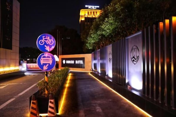 A hotel entrance with a sign indicating bicycle parking and a bus stop. - Ningbo Hotel (Ningbo)
