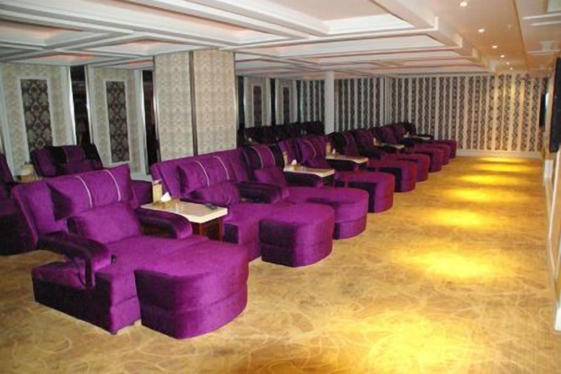 Un salón de conferencias con hileras de sillas moradas y suelo alfombrado.