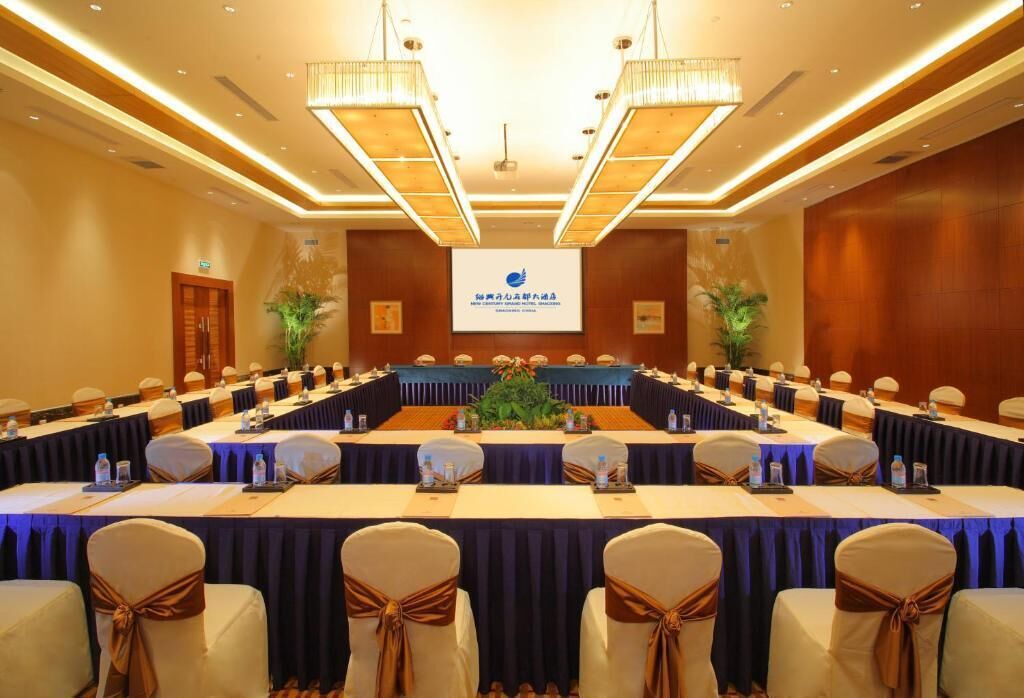 A conference room with a long table, chairs, and a presentation screen.