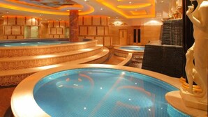 Een luxe spa-ruimte met meerdere whirlpools en een beeldhouwwerk.