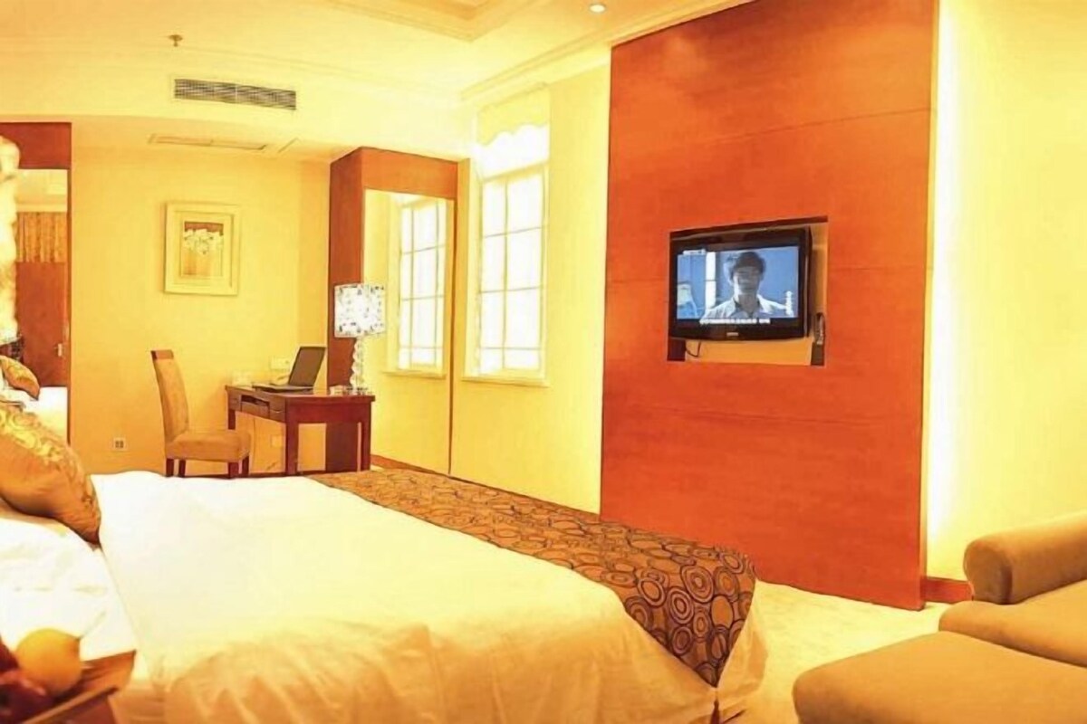 Una habitación de hotel con cama, escritorio, televisor y silla.
