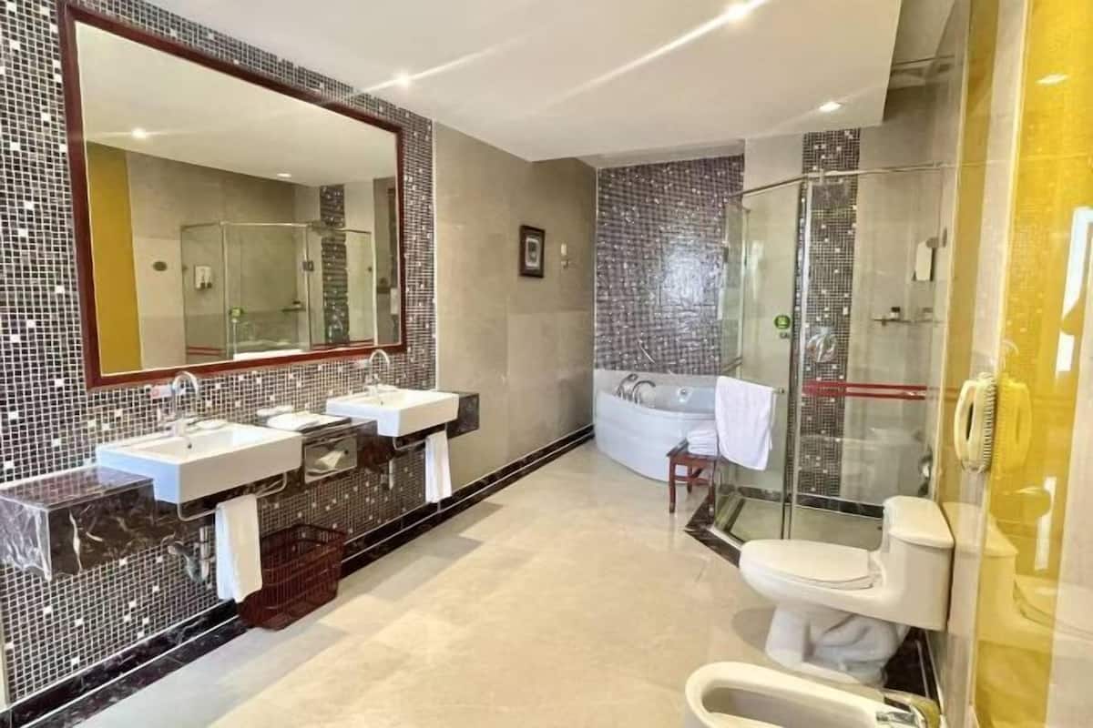 Une salle de bain moderne dotée d’un grand miroir, de trois lavabos, d’une baignoire et d’une cabine de douche en verre.