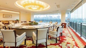 A hotel conference room with a round table, chairs, and a city view through large windows. - Liuzhou Hotel (Liuzhou)