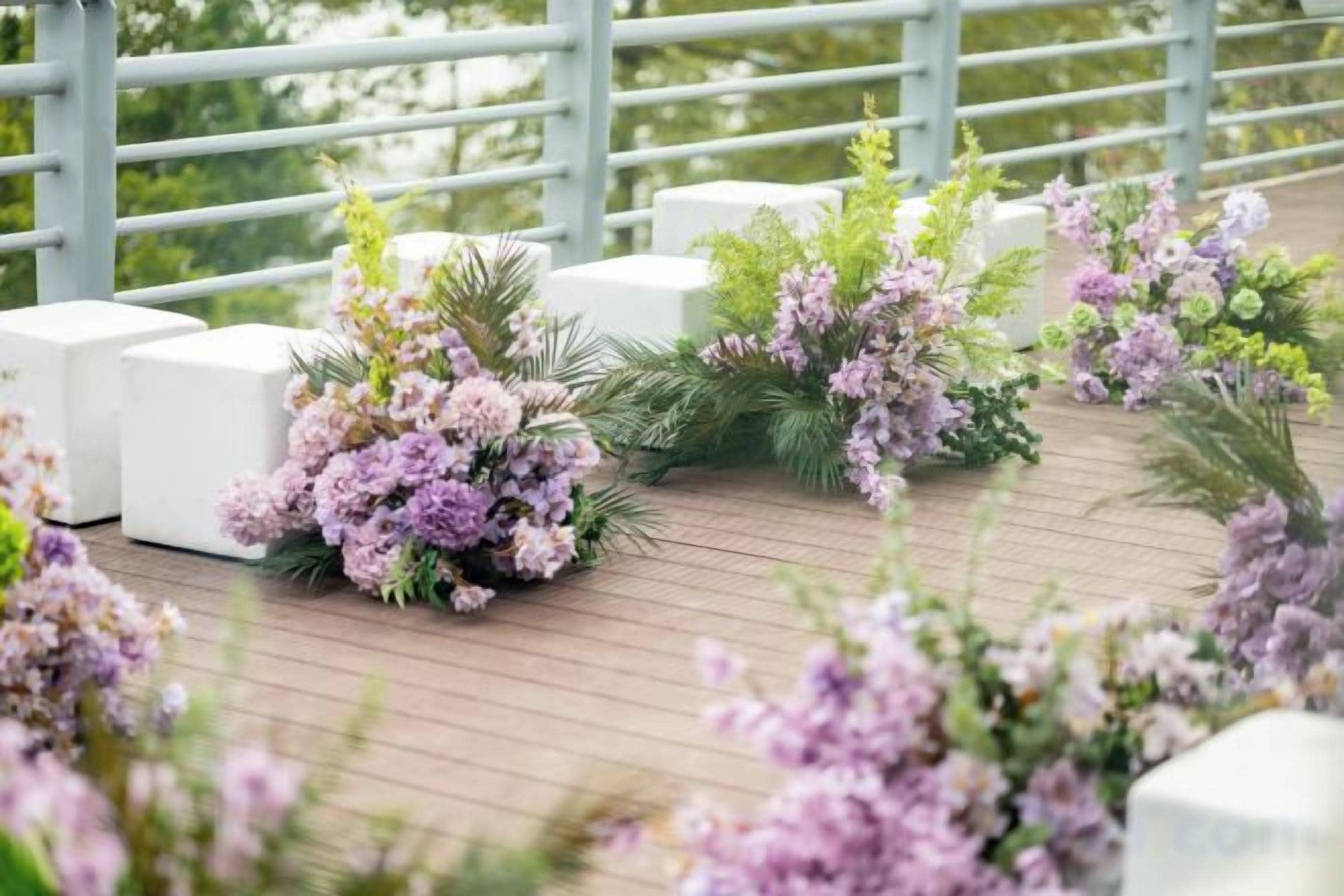 Una terraza con mobiliario blanco y arreglos florales.